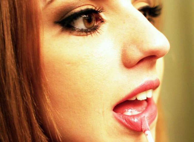 Lexi Belle face close up photo of her applying lipstick.