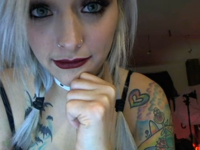 Sexy inked cam girl covered in tattoos, pierced nipples, live on webcam teasing.