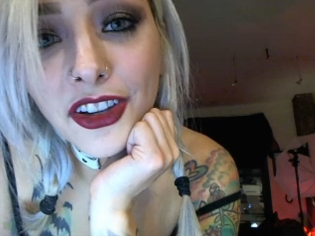 Sexy inked cam girl covered in tattoos, pierced nipples, live on webcam teasing.